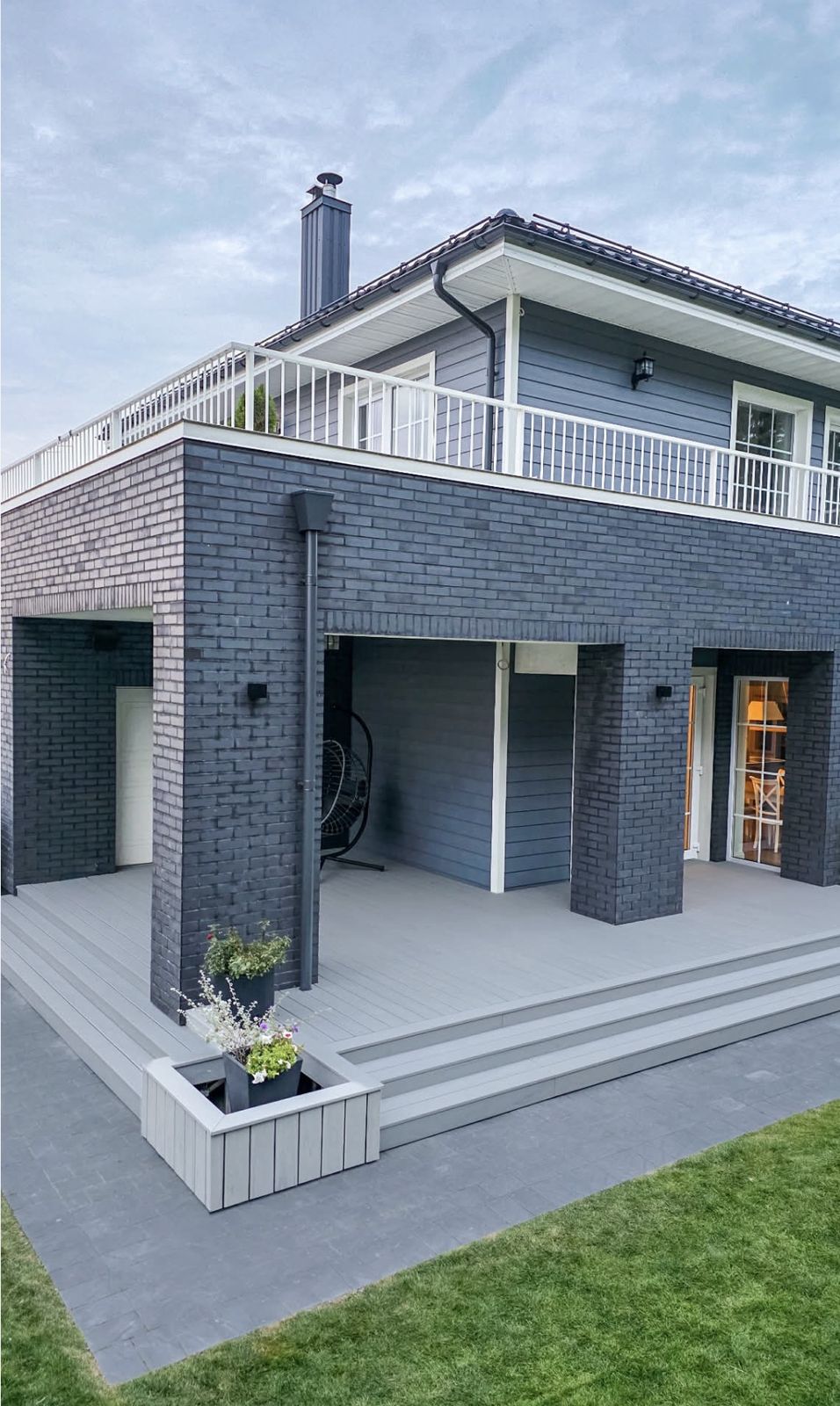 Grey composite deck with wide wraparound steps and a matching planter