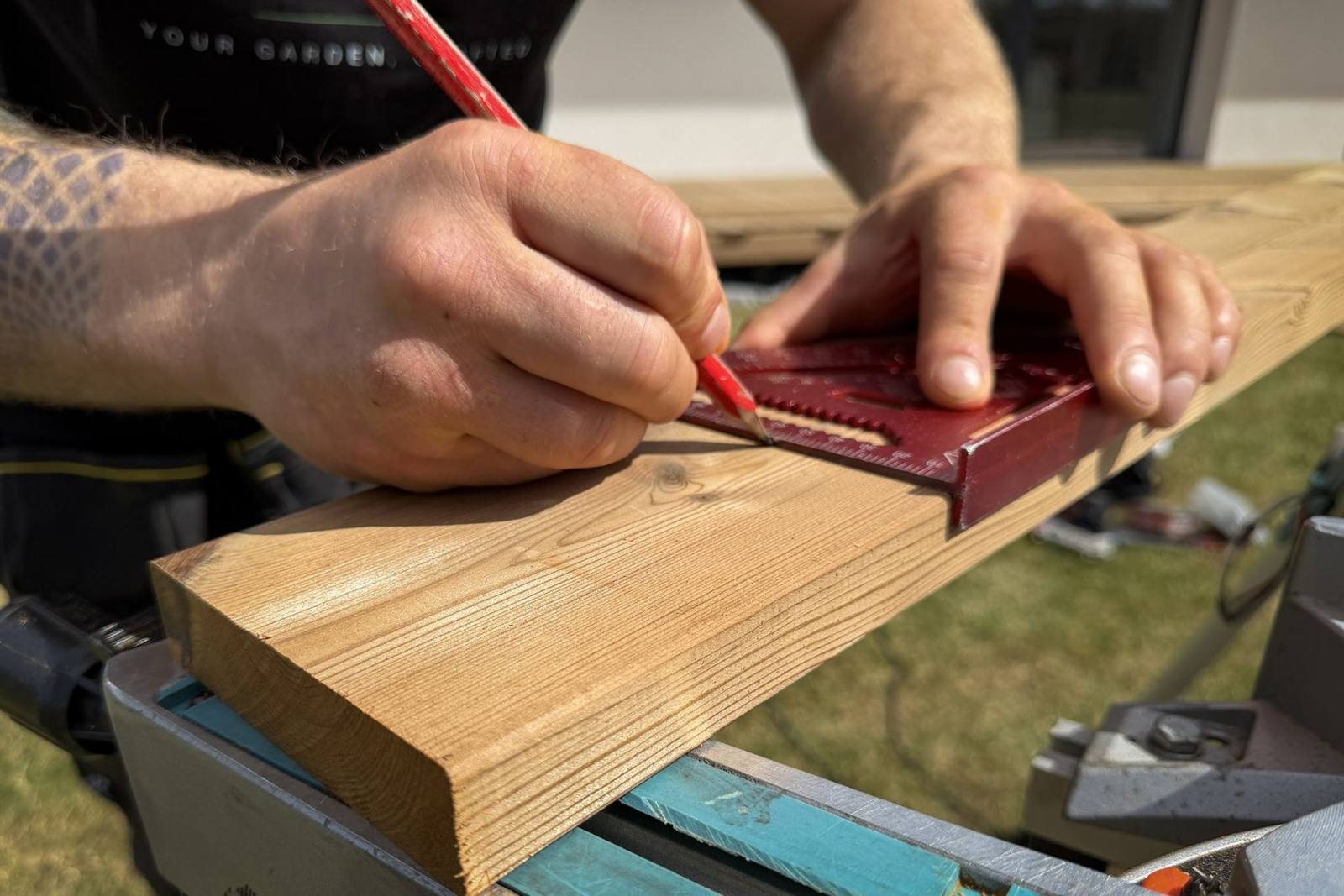 Marking a timber deck board with a square and pencil before cutting
