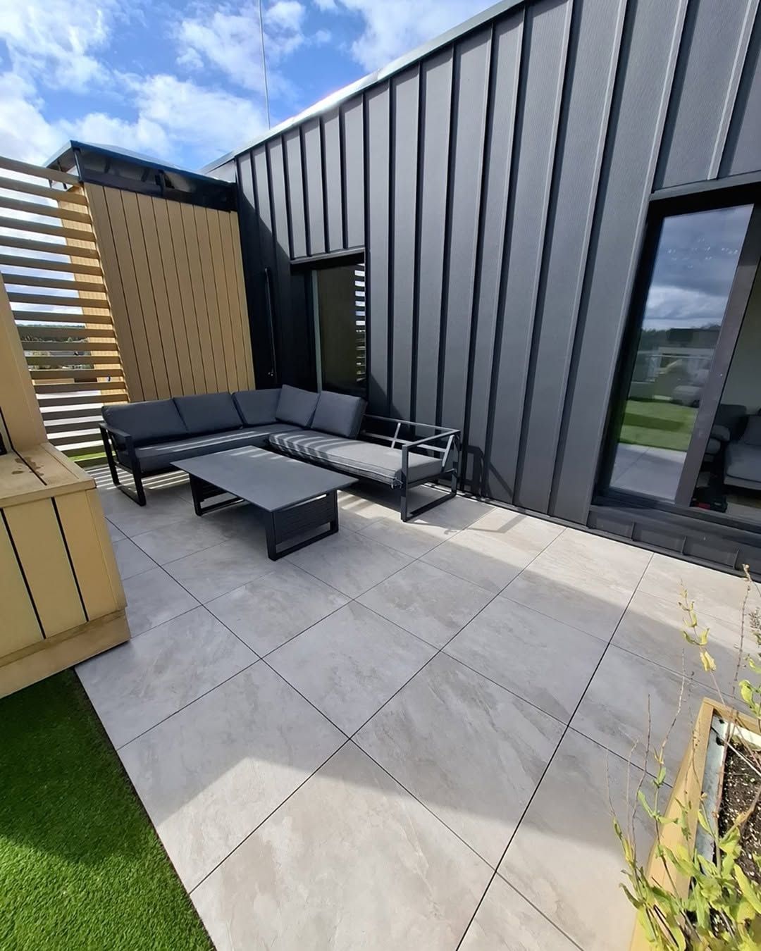 Porcelain-tiled roof terrace with an outdoor sofa, slatted timber screen and planters