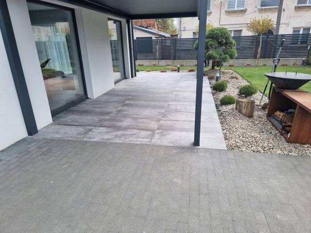Porcelain paving under an aluminium patio cover, with gravel border and clipped pine