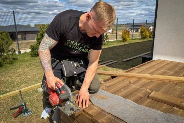 Cutting a deck board with a circular saw next to the house