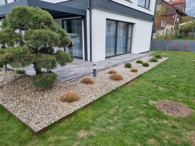 Gravel bed with steel edging, cloud-pruned pine and porcelain paving